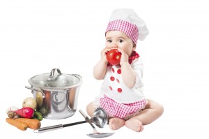 Baby girl  wearing a chef hat with vegetables and pan. Use it for a child, healthy food concept
